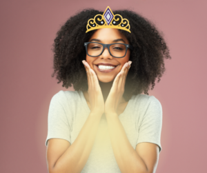 An African American woman is smiling and holding one hand to each cheek. She has a glow coming from her heart center and she is wearing a diamond crown. Her soul connection is strong.