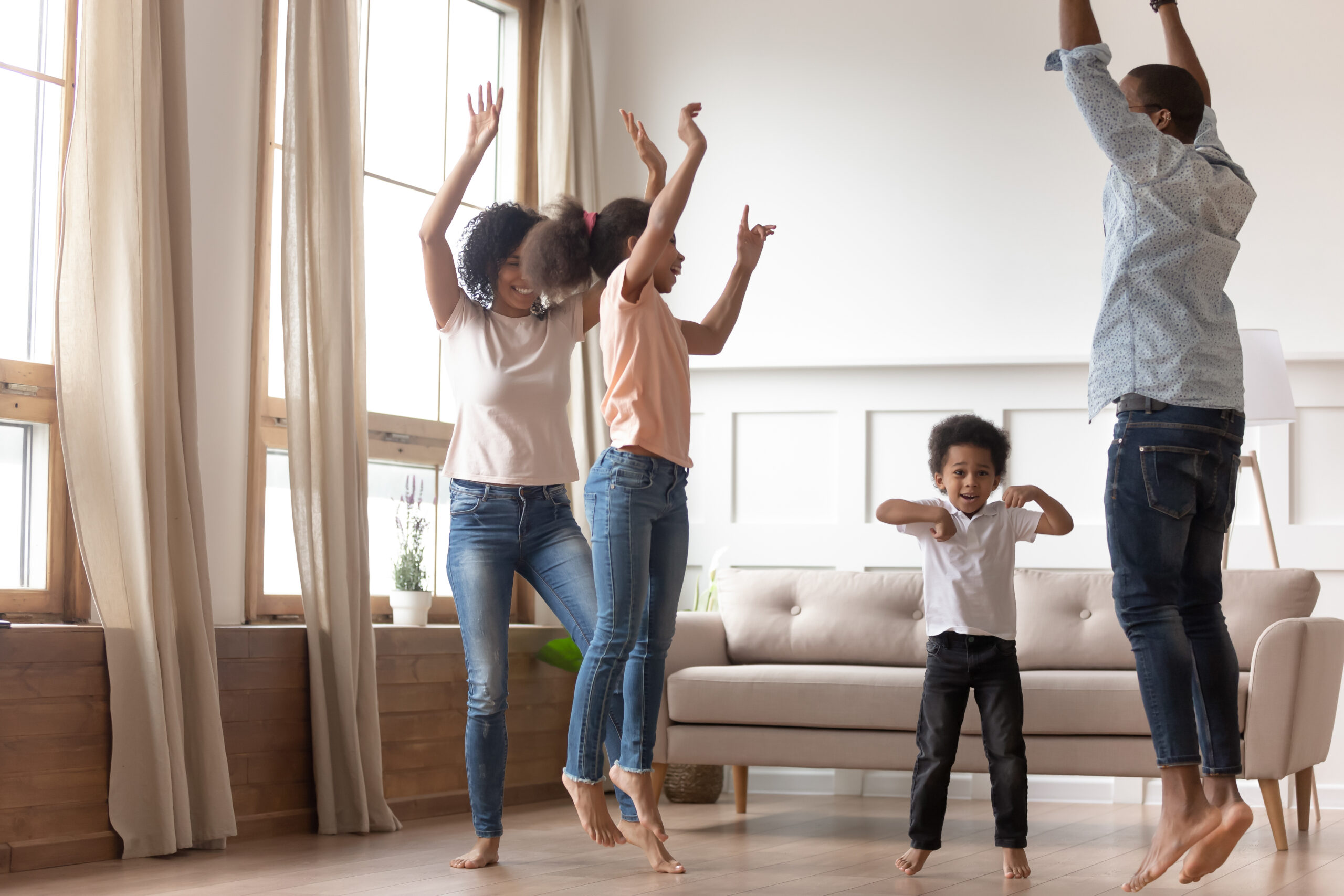 Joyful happy african family having fun jumping at home together